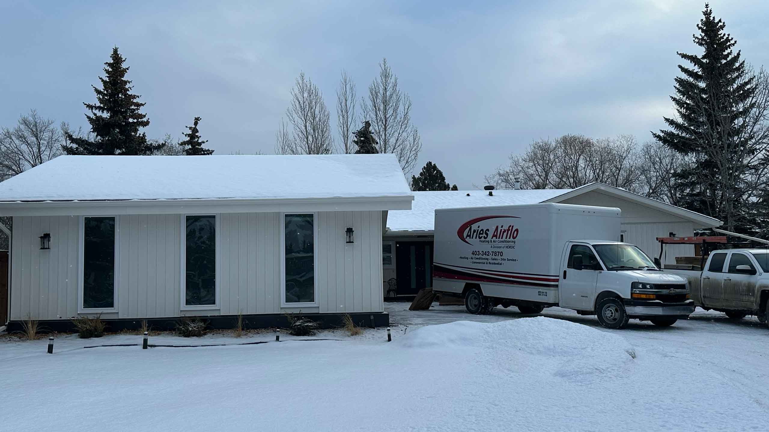 aries truck in front of a white house in winter